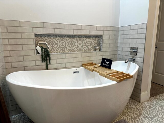 bathroom featuring tile patterned flooring, tile walls, and a freestanding bath