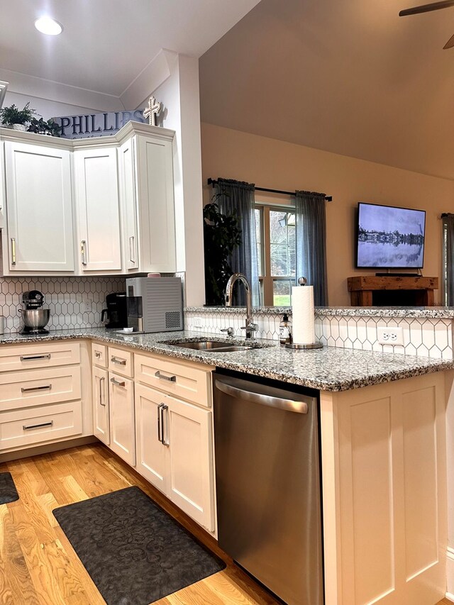 kitchen with a sink, stainless steel dishwasher, light wood-type flooring, backsplash, and light stone countertops