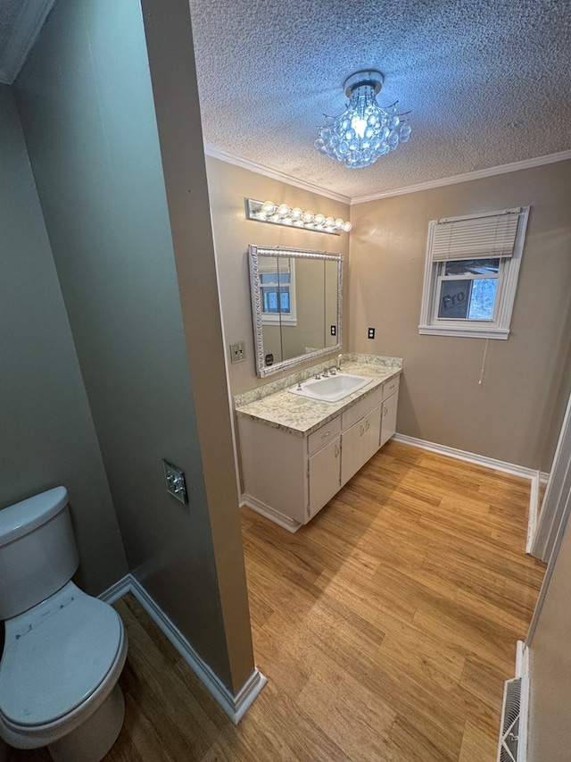 bathroom featuring toilet, ornamental molding, wood finished floors, a textured ceiling, and vanity