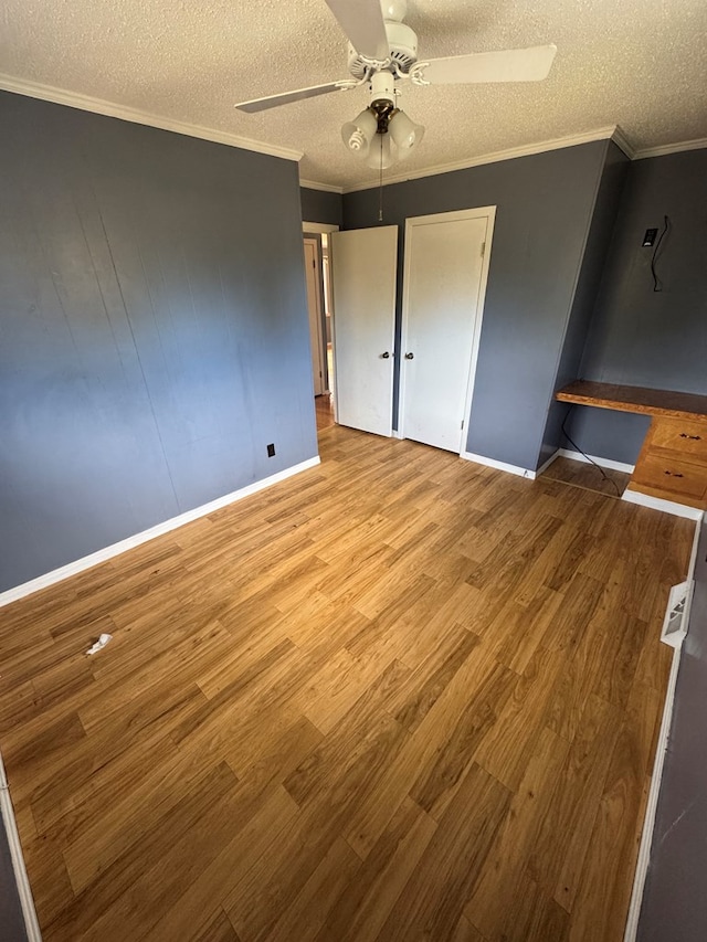 unfurnished bedroom with crown molding, light wood-style flooring, ceiling fan, a textured ceiling, and baseboards