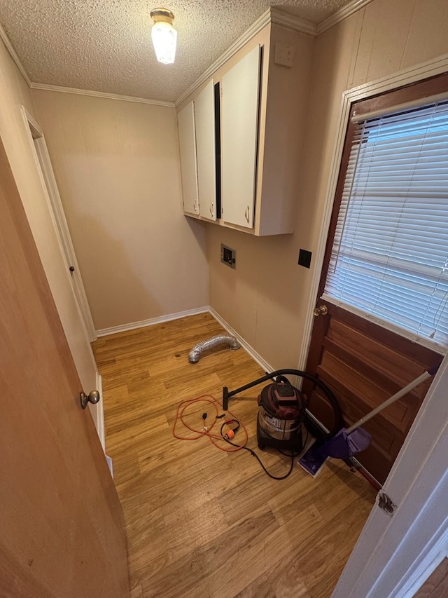 clothes washing area with light wood-style floors, a textured ceiling, washer hookup, and cabinet space