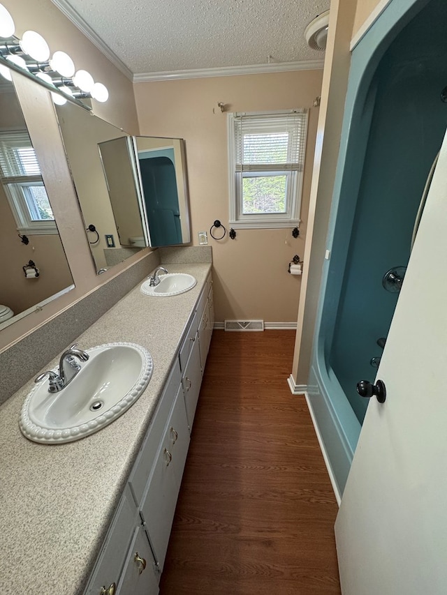 full bathroom featuring ornamental molding, visible vents, a sink, and a textured ceiling