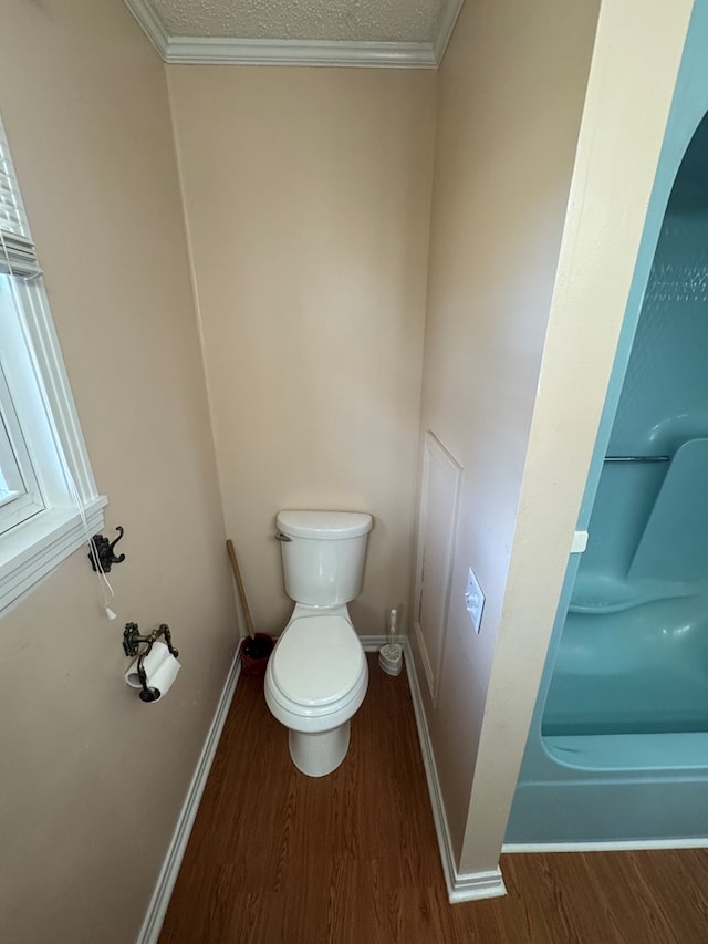 bathroom with toilet, baseboards, ornamental molding, and wood finished floors