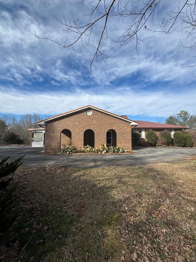 exterior space with driveway, brick siding, and a lawn