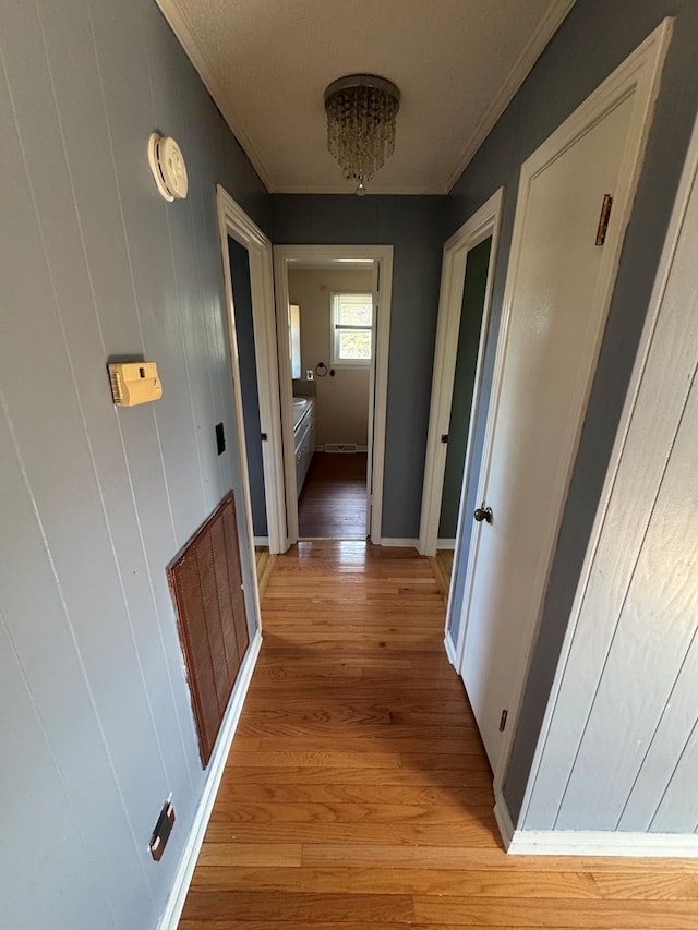 hallway with crown molding, visible vents, and light wood-style floors