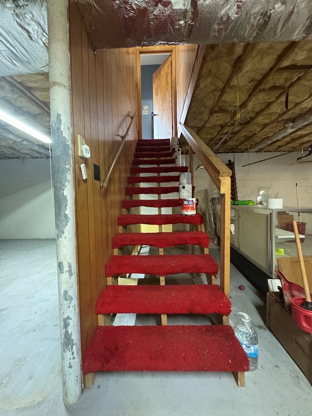 stairway with concrete flooring and wood walls