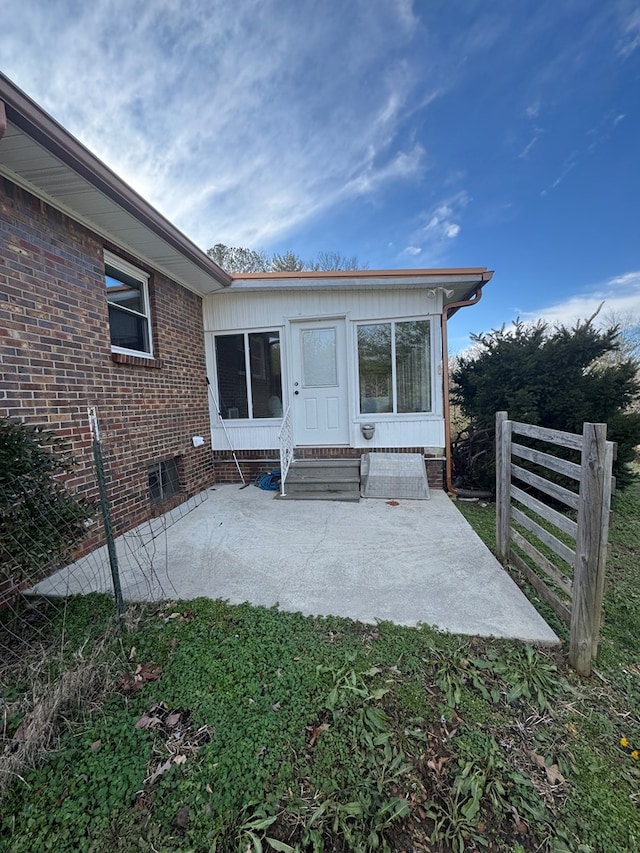 property entrance featuring brick siding and a patio