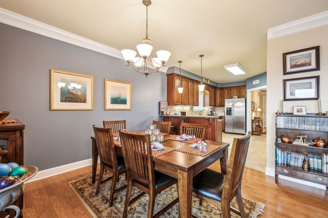 dining space featuring light wood-style flooring, baseboards, a chandelier, and crown molding