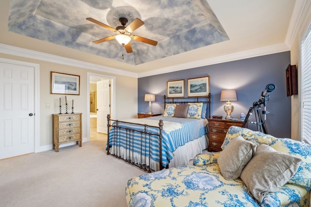 bedroom featuring a raised ceiling, light colored carpet, ceiling fan, ensuite bathroom, and crown molding