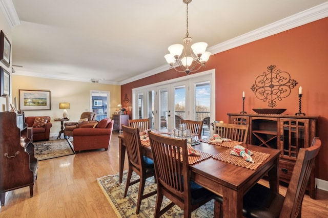 dining room featuring light wood-style floors, ornamental molding, an inviting chandelier, and french doors