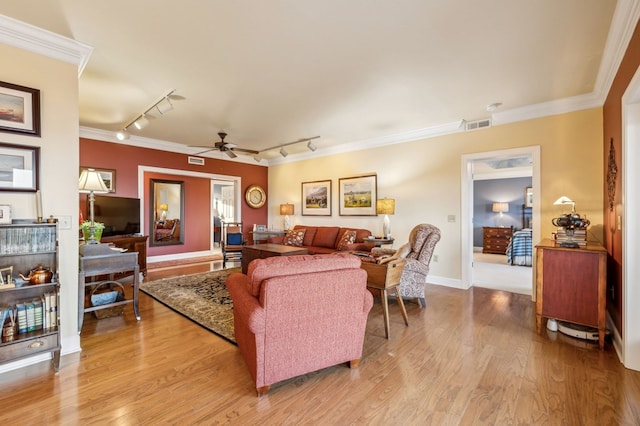 living room featuring light wood-style floors, visible vents, crown molding, and a ceiling fan