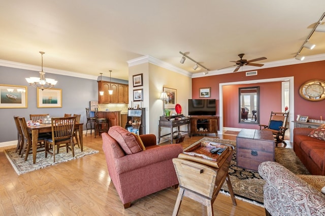 living area with light wood-type flooring, rail lighting, visible vents, and crown molding