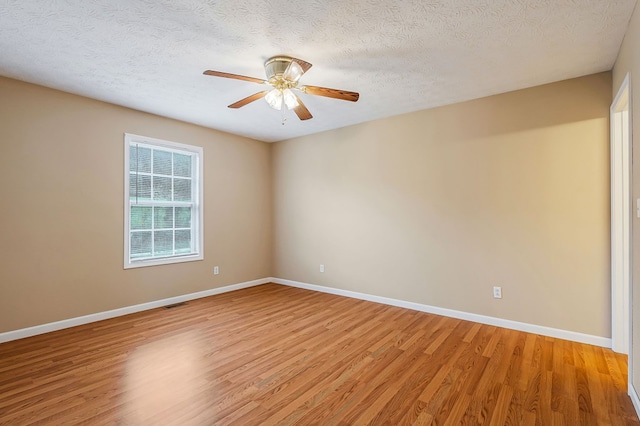 empty room with light wood finished floors, visible vents, baseboards, ceiling fan, and a textured ceiling