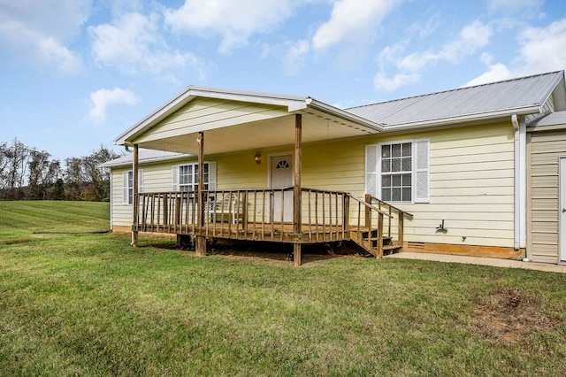 back of property with metal roof, a wooden deck, and a lawn