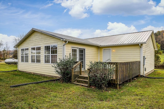 rear view of house with metal roof and a yard