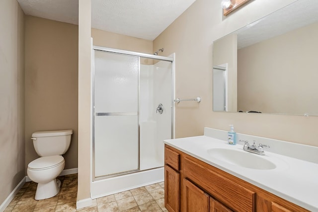 full bath featuring a textured ceiling, toilet, vanity, baseboards, and a stall shower