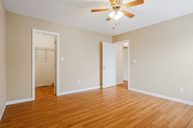 unfurnished bedroom with light wood-type flooring, baseboards, and a walk in closet