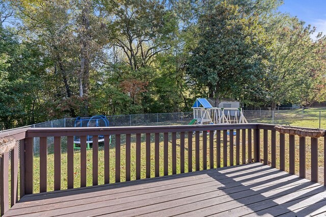 wooden terrace featuring a fenced backyard, a playground, and a yard