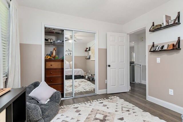 bedroom with dark wood-type flooring, a closet, a textured ceiling, and baseboards