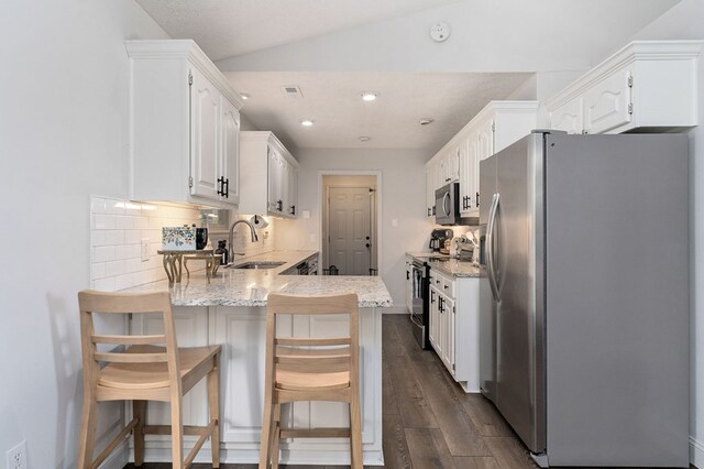 kitchen with decorative backsplash, a breakfast bar area, appliances with stainless steel finishes, white cabinetry, and a sink