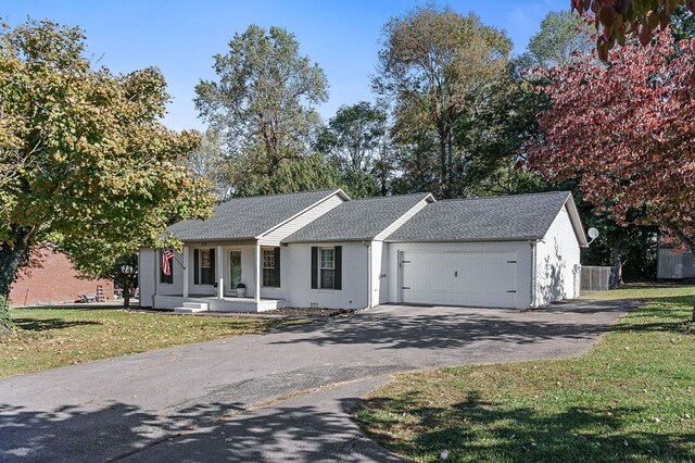 ranch-style home with brick siding, covered porch, an attached garage, a front yard, and driveway