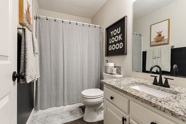 full bathroom with a textured ceiling, vanity, and toilet