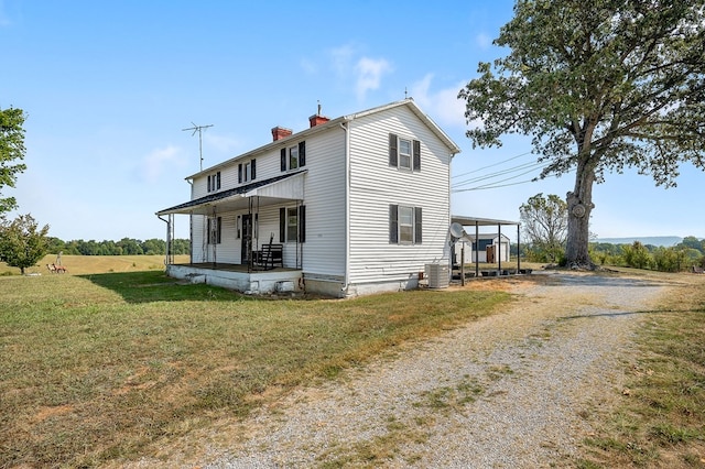 exterior space featuring a chimney, a porch, central AC unit, driveway, and a front lawn