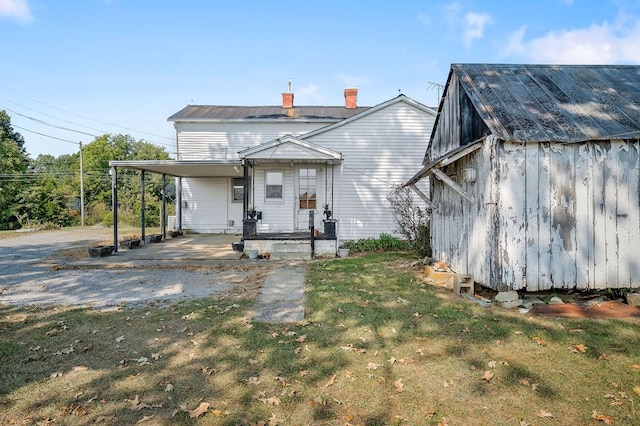 view of front of house featuring a front yard, a chimney, metal roof, and driveway