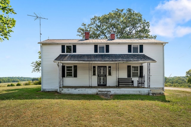 view of front of property with metal roof, covered porch, a front lawn, a standing seam roof, and a chimney