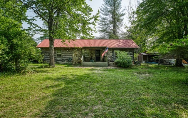 rear view of property featuring stone siding, metal roof, and a yard