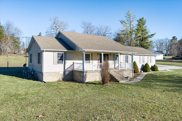 ranch-style home with covered porch, roof with shingles, and a front yard