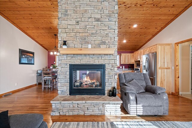 living area with a stone fireplace, ornamental molding, light wood-type flooring, and wooden ceiling