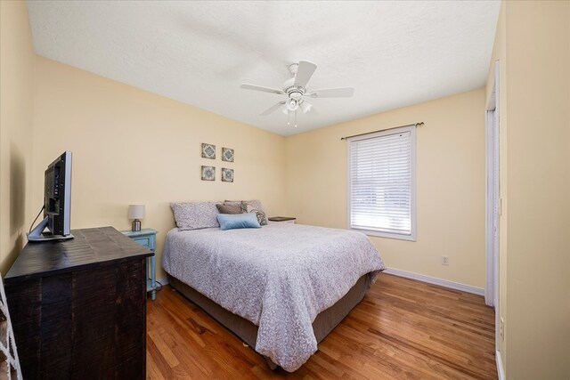 bedroom with dark wood-type flooring, a textured ceiling, and baseboards