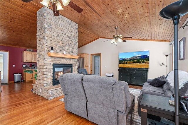 living room with ceiling fan, a stone fireplace, light wood-type flooring, and lofted ceiling