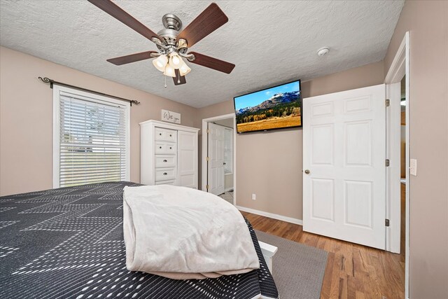 bedroom featuring a textured ceiling, wood finished floors, a ceiling fan, and baseboards