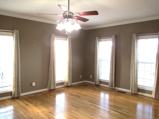 empty room featuring visible vents, crown molding, and light wood-style flooring