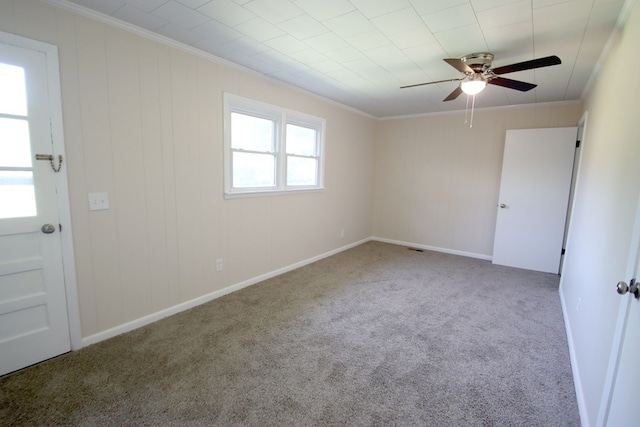 empty room with ornamental molding, carpet, baseboards, and a ceiling fan