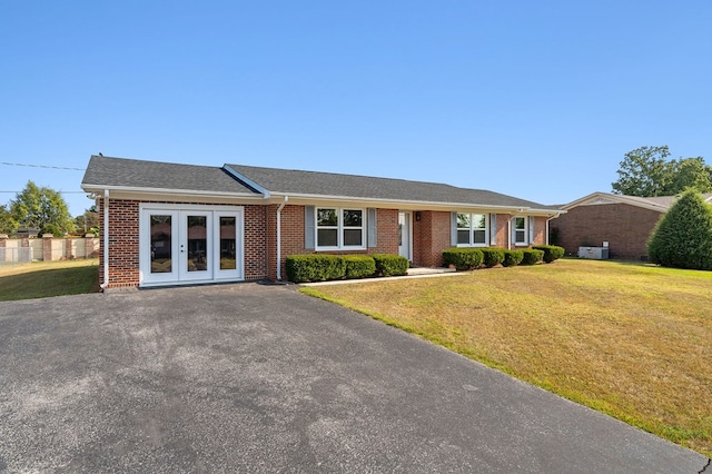 ranch-style home with brick siding, fence, a front lawn, and french doors