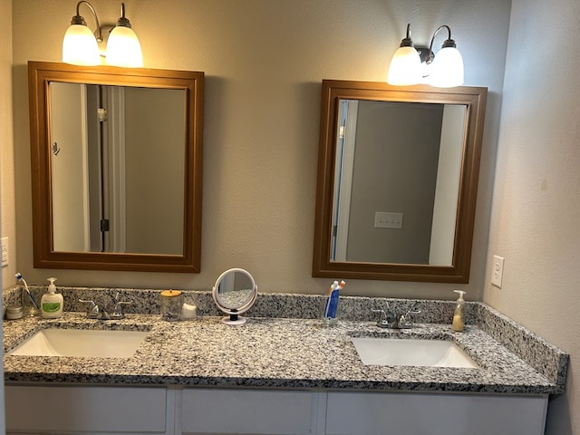 full bathroom with a textured wall, double vanity, and a sink