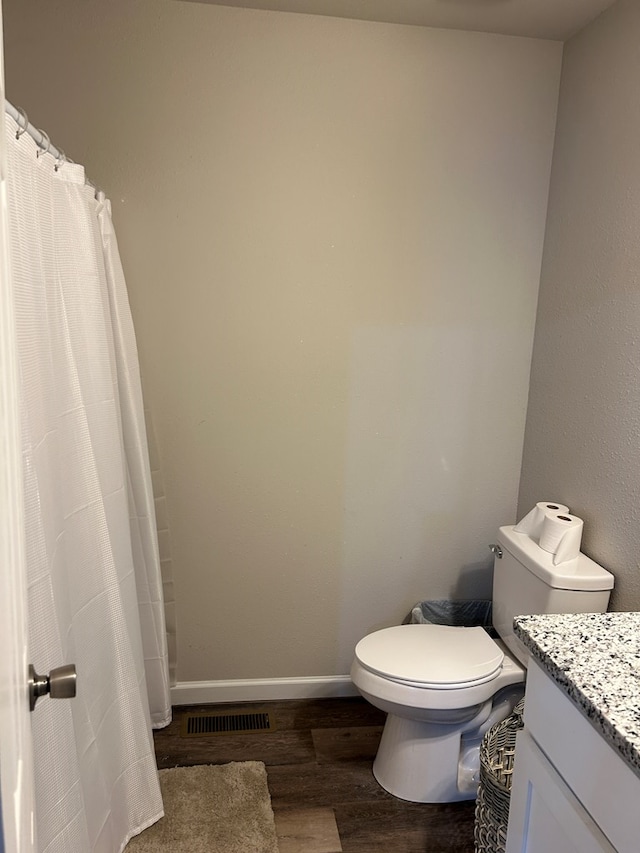 bathroom with toilet, wood finished floors, visible vents, vanity, and baseboards