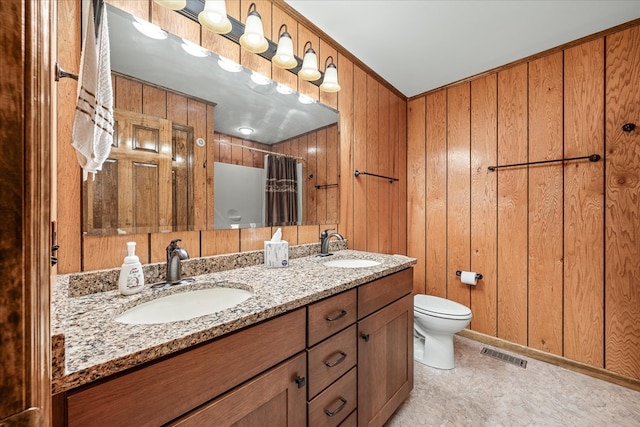 bathroom with toilet, double vanity, visible vents, and a sink