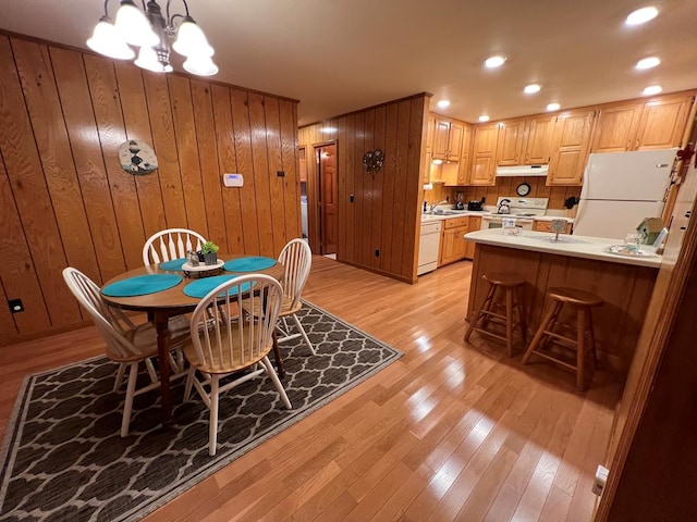 dining area featuring recessed lighting, wood walls, light wood-type flooring, and a notable chandelier