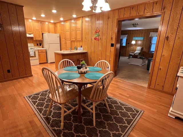 dining room featuring wooden walls, an inviting chandelier, and light wood-style floors