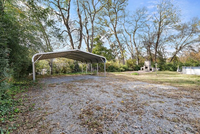 view of yard with gravel driveway, a fireplace, and a detached carport