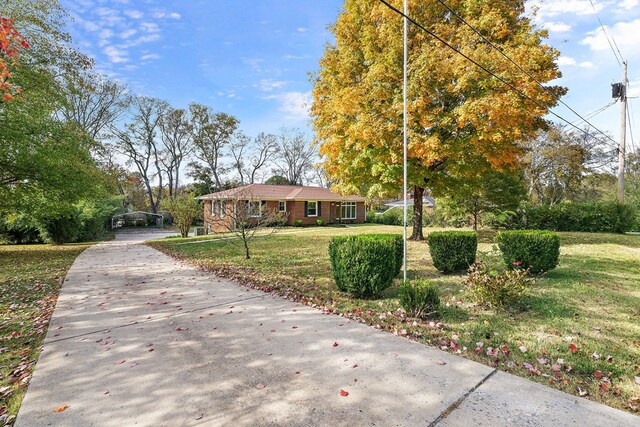 view of front of house featuring brick siding, concrete driveway, and a front yard