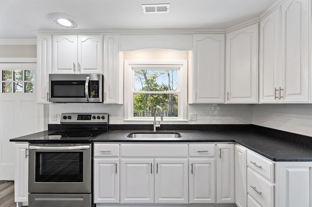 kitchen featuring stainless steel appliances, dark countertops, white cabinets, and a sink