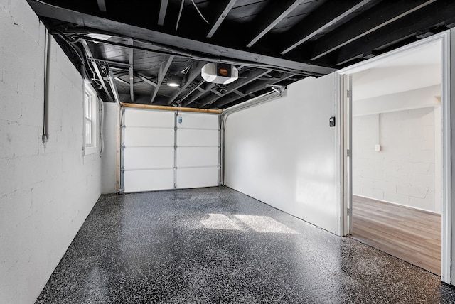 garage featuring concrete block wall and a garage door opener