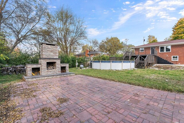 view of patio with stairway, an outdoor stone fireplace, and an outdoor pool