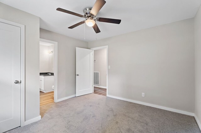 unfurnished bedroom with baseboards, visible vents, a ceiling fan, and light colored carpet