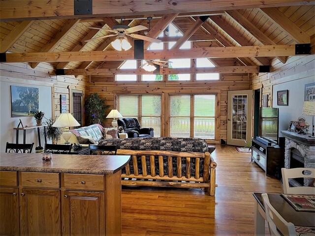 living room with wooden walls, light wood-style flooring, a fireplace, wood ceiling, and beamed ceiling